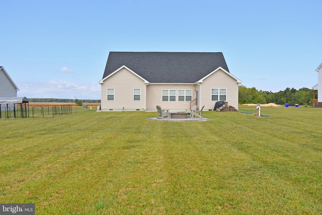 rear view of house with an outdoor fire pit and a lawn