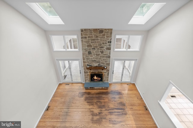 unfurnished living room with a fireplace, a towering ceiling, and hardwood / wood-style flooring