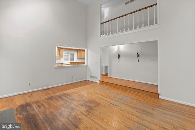 unfurnished living room with light hardwood / wood-style floors and a high ceiling