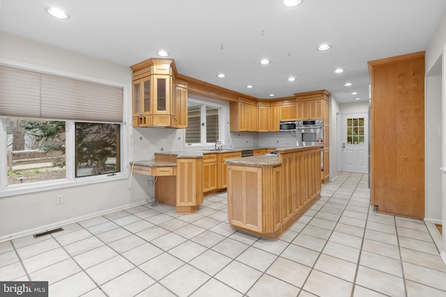 kitchen featuring light stone countertops, a center island, plenty of natural light, and sink