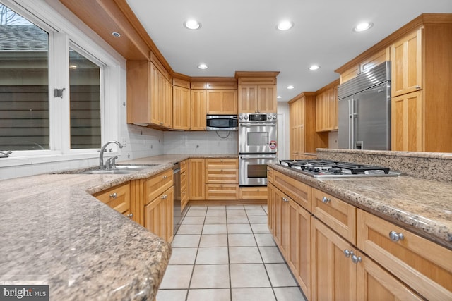 kitchen featuring light stone countertops, sink, stainless steel appliances, decorative backsplash, and light tile patterned floors