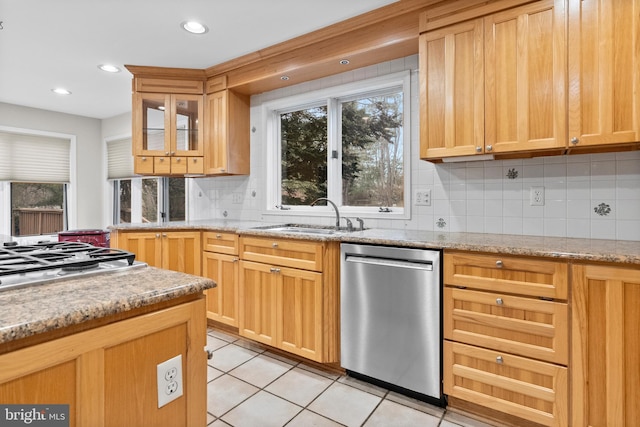 kitchen featuring appliances with stainless steel finishes, tasteful backsplash, light stone counters, sink, and light tile patterned floors