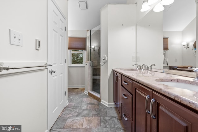 bathroom featuring a shower with door and vanity