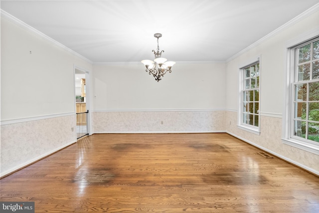 empty room featuring a notable chandelier, a healthy amount of sunlight, and crown molding