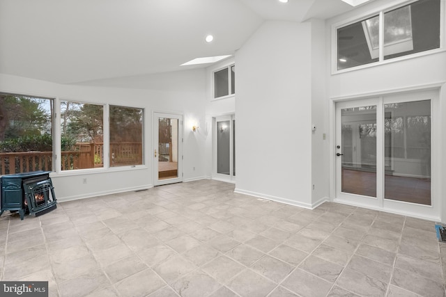 unfurnished sunroom featuring a wood stove and lofted ceiling with skylight