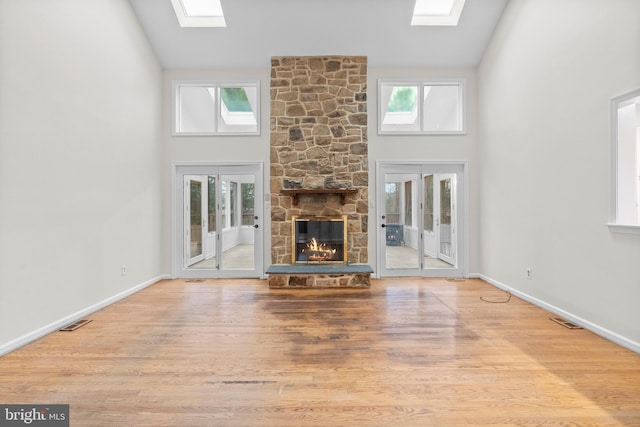 unfurnished living room featuring a skylight, a fireplace, and high vaulted ceiling