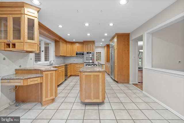 kitchen with kitchen peninsula, a center island, light stone countertops, and stainless steel appliances