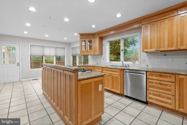 kitchen with appliances with stainless steel finishes, a center island, light stone counters, and sink