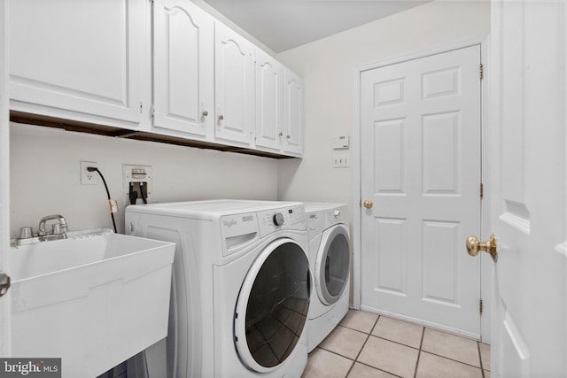 laundry area with light tile patterned flooring, cabinets, sink, and washing machine and clothes dryer