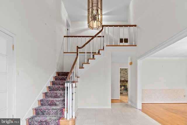 stairway with a notable chandelier, a fireplace, and a high ceiling