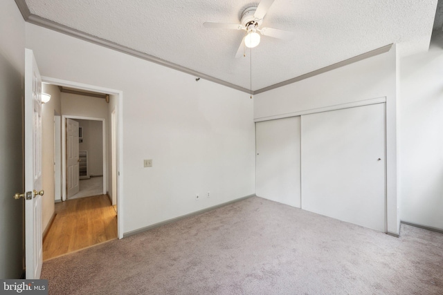 unfurnished bedroom with a textured ceiling, carpet flooring, and ceiling fan