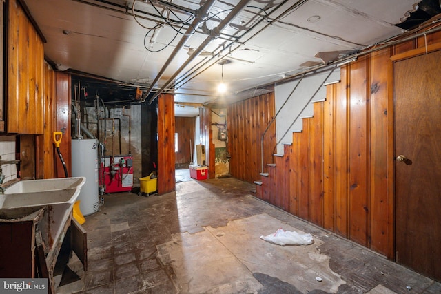 basement featuring water heater and wood walls