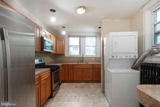 laundry room with radiator heating unit, sink, and stacked washer and clothes dryer