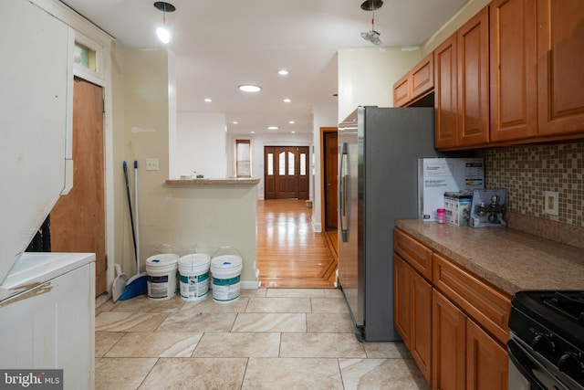 kitchen featuring black range oven, backsplash, stainless steel refrigerator, pendant lighting, and light wood-type flooring