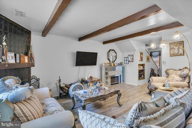 living room with a notable chandelier, hardwood / wood-style flooring, and vaulted ceiling with beams