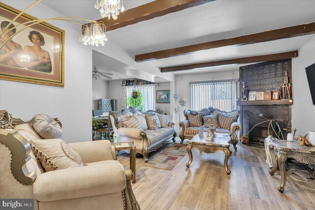 living room featuring light hardwood / wood-style flooring, beamed ceiling, and a chandelier