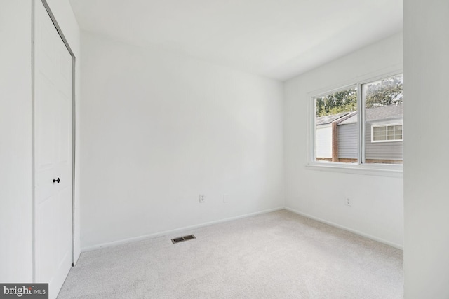 unfurnished bedroom featuring light carpet and a closet