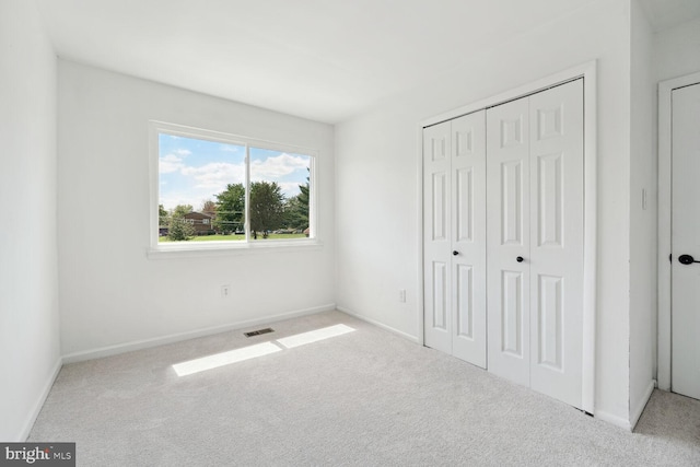 unfurnished bedroom with a closet and light colored carpet