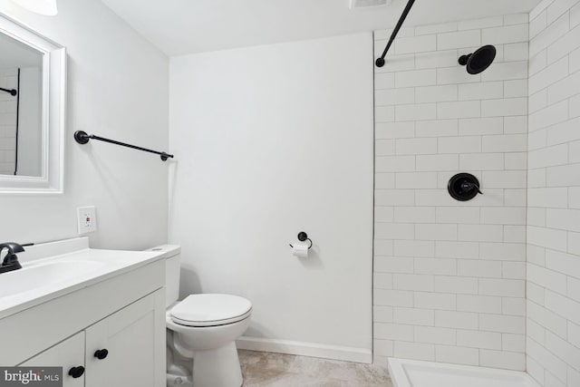 bathroom featuring tile patterned floors, vanity, toilet, and tiled shower