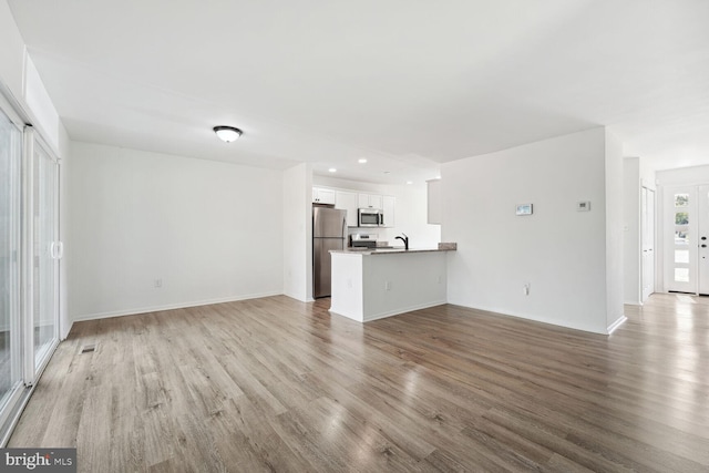 unfurnished living room with sink and hardwood / wood-style floors