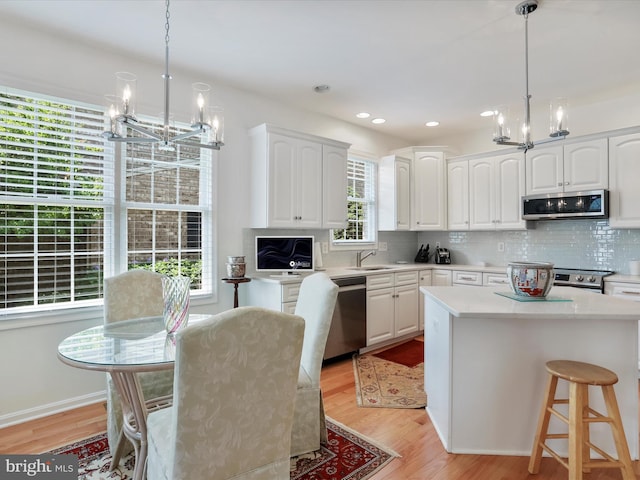 kitchen with white cabinetry, appliances with stainless steel finishes, and decorative light fixtures