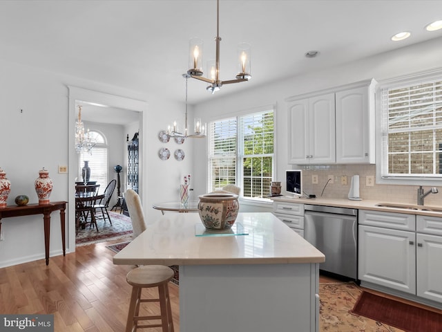 kitchen with stainless steel dishwasher, sink, white cabinets, and a center island