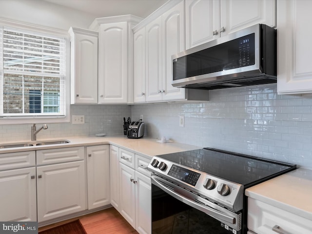 kitchen featuring white cabinets, decorative backsplash, stainless steel appliances, and sink