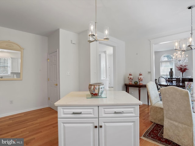 kitchen with hanging light fixtures, white cabinetry, a kitchen island, and a notable chandelier