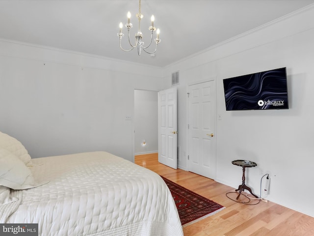 bedroom featuring an inviting chandelier, hardwood / wood-style flooring, and crown molding