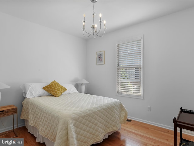 bedroom with wood-type flooring and a notable chandelier