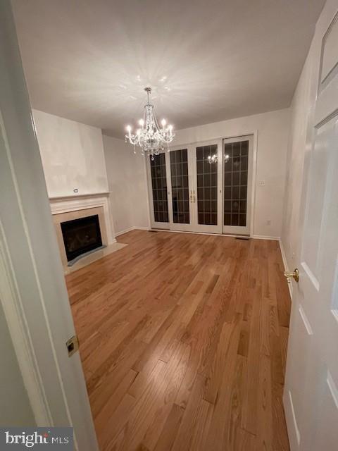 unfurnished living room with a chandelier and hardwood / wood-style floors