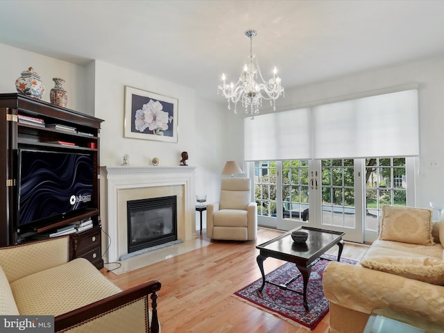 living room featuring an inviting chandelier, light wood-type flooring, and french doors