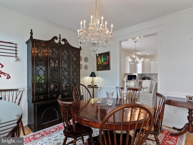 dining area with ornamental molding, an inviting chandelier, and light hardwood / wood-style flooring