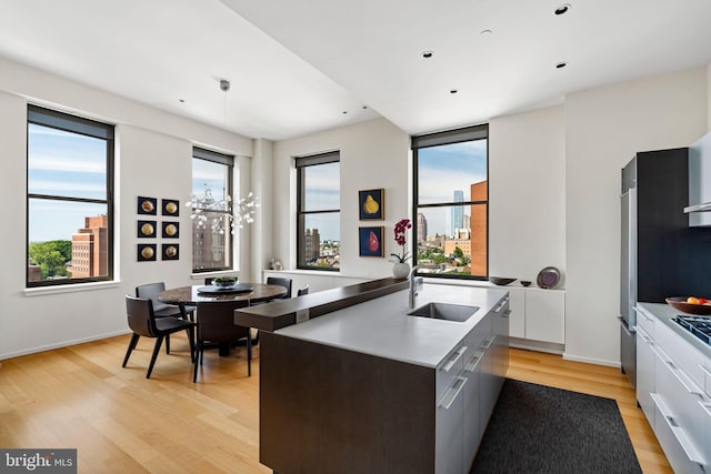 kitchen featuring white cabinets, an island with sink, sink, and light hardwood / wood-style floors