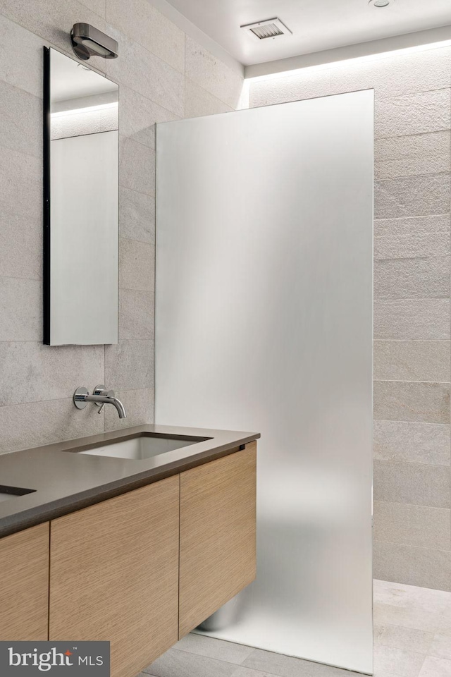 bathroom with tile patterned floors, tile walls, and vanity