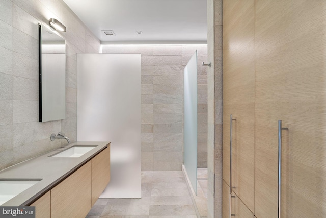 bathroom featuring tile walls, double vanity, a shower, and tile patterned flooring