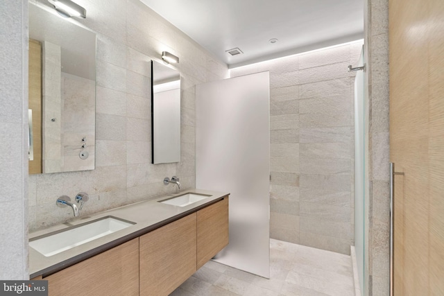 bathroom with dual vanity, tile patterned floors, tile walls, and walk in shower