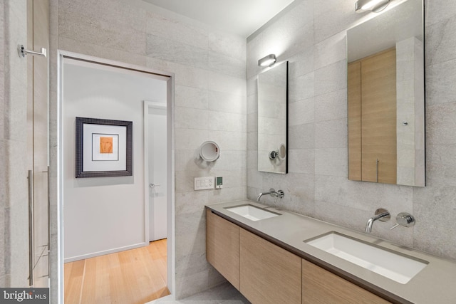 bathroom featuring dual bowl vanity, tile walls, and hardwood / wood-style floors