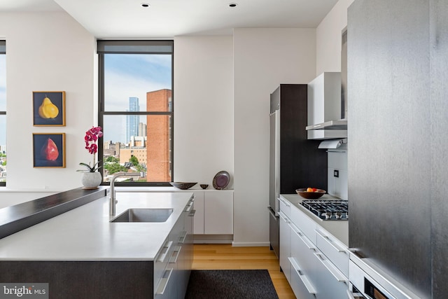 kitchen with stovetop, white cabinets, light hardwood / wood-style flooring, sink, and refrigerator