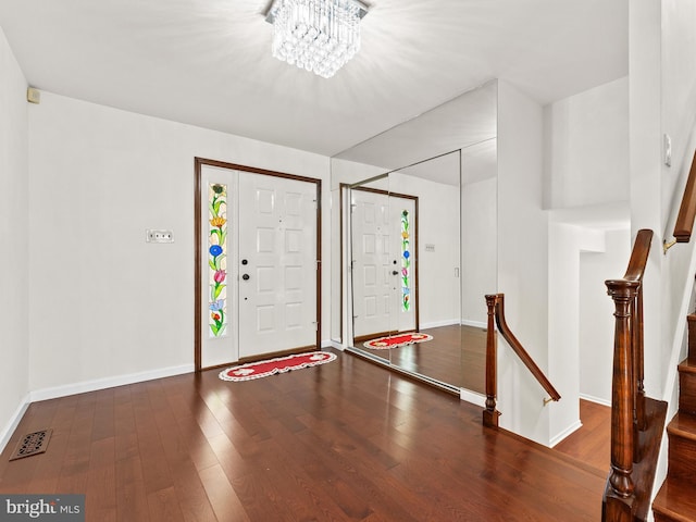 entryway featuring dark wood-type flooring and a chandelier