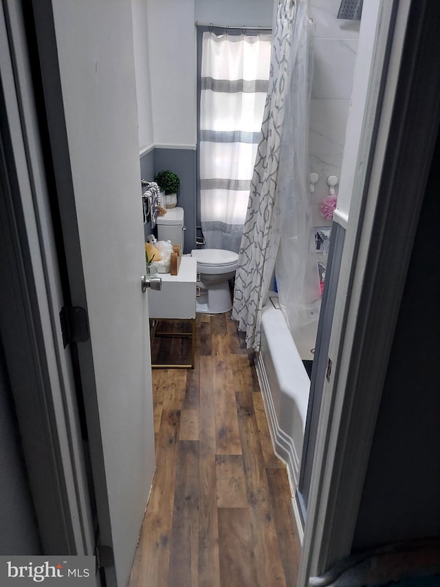 bathroom featuring toilet, wood-type flooring, and shower / tub combo