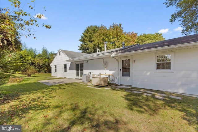 rear view of property with central AC unit, a yard, and a patio