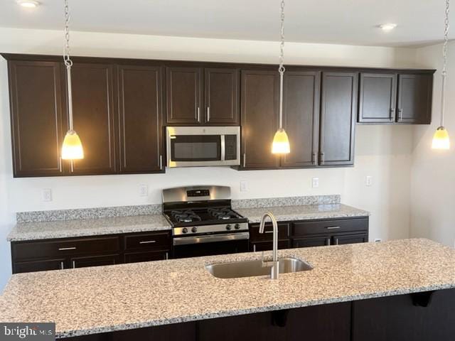 kitchen with hanging light fixtures, dark brown cabinets, sink, and appliances with stainless steel finishes