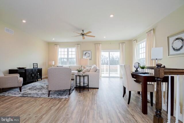 living room featuring light hardwood / wood-style flooring, ceiling fan, and a healthy amount of sunlight