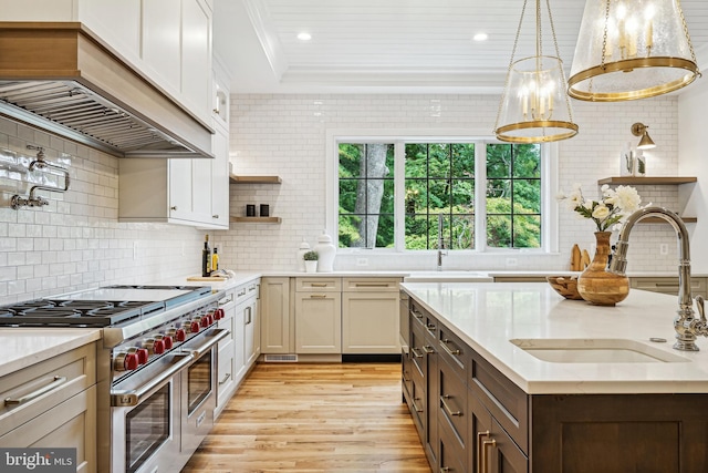 kitchen with sink, backsplash, range with two ovens, custom exhaust hood, and light wood-type flooring