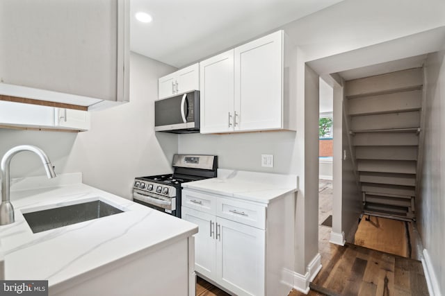 kitchen with light stone counters, appliances with stainless steel finishes, dark wood-type flooring, and white cabinets