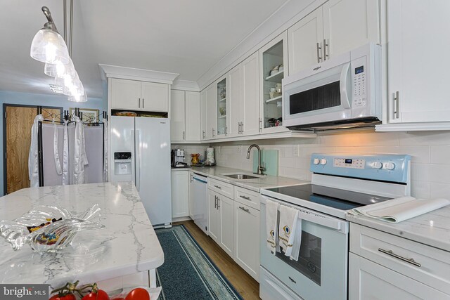 kitchen featuring white appliances, hardwood / wood-style floors, sink, backsplash, and white cabinetry