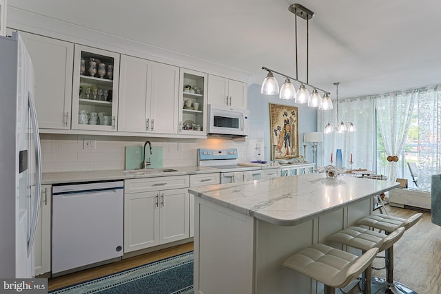 kitchen with white appliances, sink, a kitchen breakfast bar, and decorative backsplash