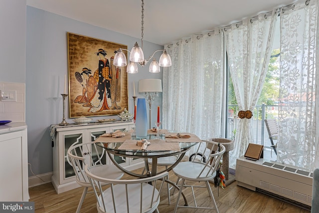 dining room featuring a notable chandelier, light hardwood / wood-style flooring, and radiator heating unit