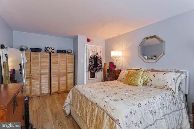 bedroom with light wood-type flooring, a walk in closet, and a closet